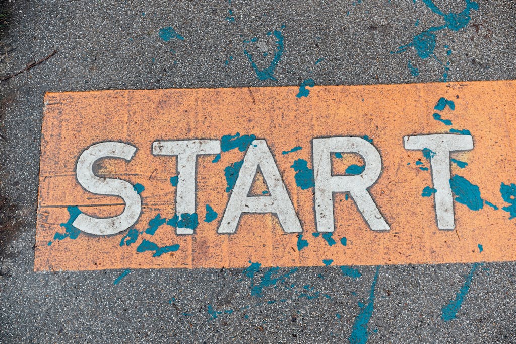 A worn orange start line painted on urban pavement with blue splatters.